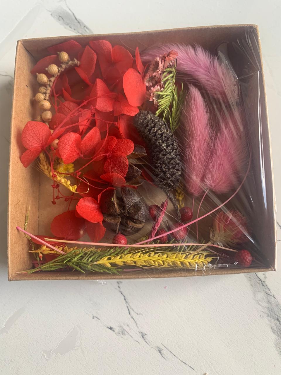 Box containing dried flowers, leaves, and feathers